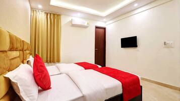 Een hotelkamer met een bed, een televisie, een airconditioning en een deur.