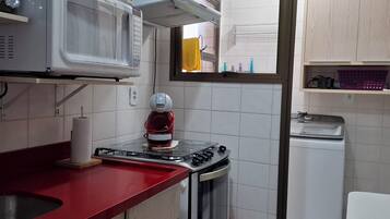 Una cucina compatta con forno a microonde, fornello e lavastoviglie.
