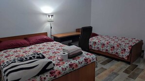 Una habitación con dos camas, un escritorio, una silla y una lámpara en la pared.