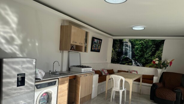 Cocina compacta con lavadora, lavaplatos y comedor con mesa y sillas.