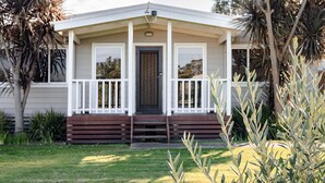 Una casa de un piso con un porche delantero, una puerta y un pequeño jardín con plantas.