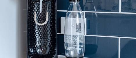 A water dispenser and a bottle on a counter with a tiled backsplash.