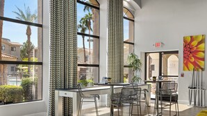 Quarto moderno com grandes janelas, um espaço bar e um sofá amarelo.