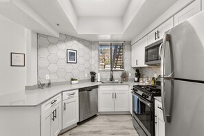 Een moderne keuken met witte kasten, roestvrijstalen apparatuur en een backsplash van hexagontegels.