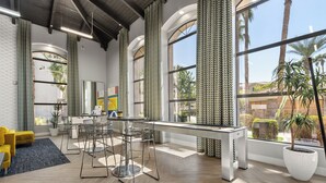 Um interior moderno com área de jantar, sofá amarelo e grandes janelas com cortinas.