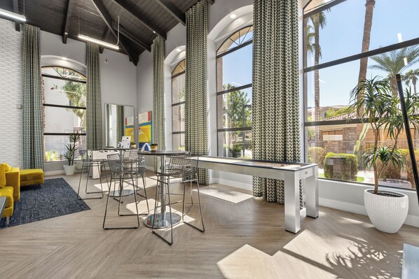 A modern interior with a dining area, yellow sofa, and large windows with curtains.