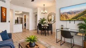 A modern living room with a sofa, coffee table, and a dining area with chairs and a table.