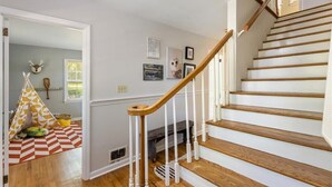 A staircase with wooden steps and white railings, leading to a landing with a fireplace. - 5BR Woodland Retreat Kayak Fish Pond Rest (North Augusta)