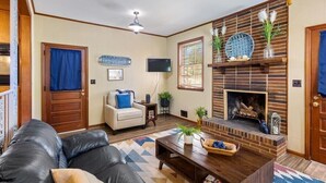 A living room with a fireplace, a sofa, a coffee table, and a television. - 5BR Woodland Retreat Kayak Fish Pond Rest (North Augusta)