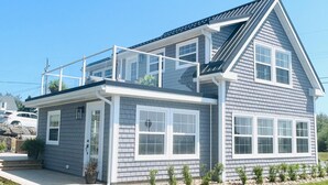 A two-story house with a balcony, large windows, and a well-maintained lawn. - Coastal Gale (Lunenburg)