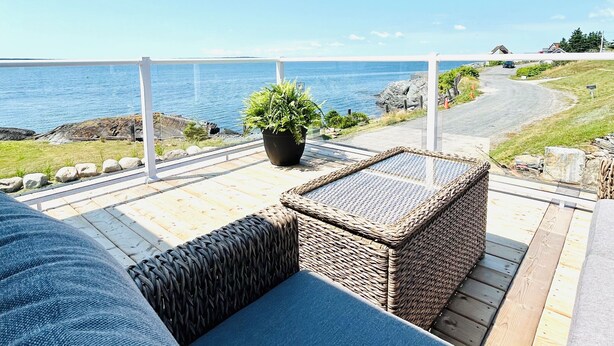 A balcony with wicker furniture, a potted plant, and a view of the sea. - Coastal Gale (Lunenburg)