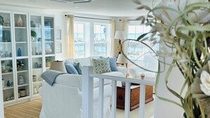 A modern living room with a white sofa, a wooden coffee table, and a glass cabinet filled with decorative items. - Coastal Gale (Lunenburg)
