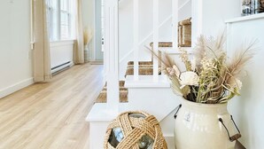 A staircase with white railings and a vase with dried flowers on the landing. - Coastal Gale (Lunenburg)