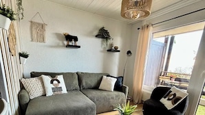A modern living room with a sectional sofa, a black bean bag chair, a coffee table with a plant, and a hanging light fixture. - Vue imprenable sur les Alpes (Crans-Montana)