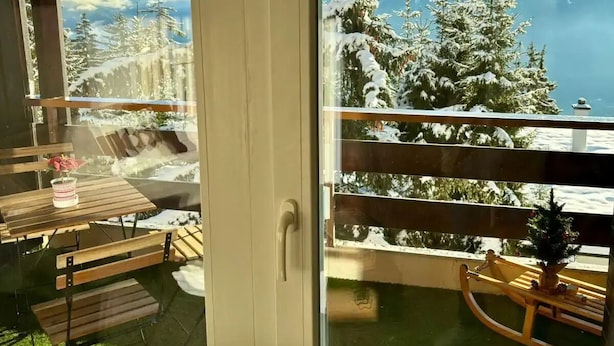 A balcony with a view of snow-covered trees and mountains. - Vue imprenable sur les Alpes (Crans-Montana)