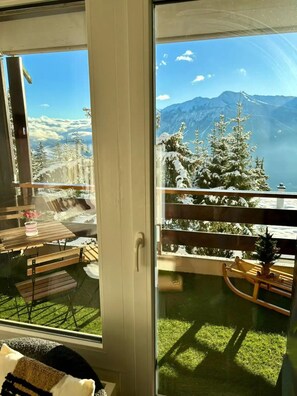 A balcony with a view of snow-covered trees and mountains. - Vue imprenable sur les Alpes (Crans-Montana)