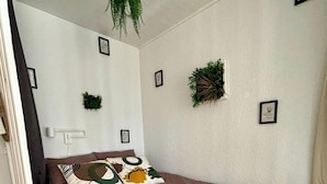 A bedroom with a bed, pillows, a hanging plant, and framed pictures on the wall. - Vue imprenable sur les Alpes (Crans-Montana)