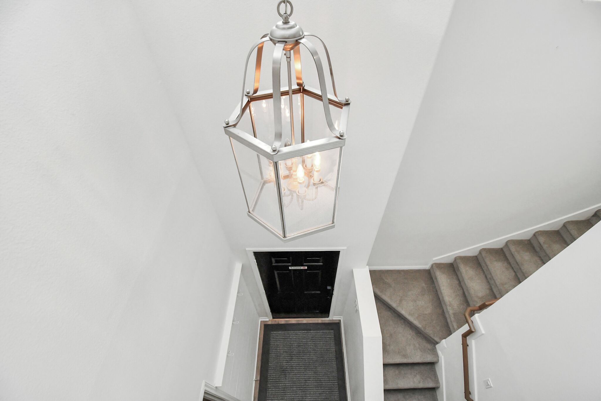 A staircase with a clear glass lantern hanging from the ceiling.