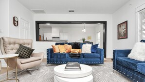 Una sala de estar moderna con un sillón color beige, un sofá azul y una mesa de centro blanca.