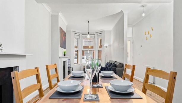 Un espace repas avec une longue table dressée pour six personnes, entourée de chaises en bois.