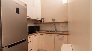A compact kitchen with a stainless steel refrigerator, a microwave, and a sink. - Sand by Grand Apartments (Sopot)