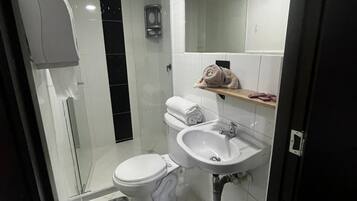 Un baño moderno con inodoro, lavamanos y cabina de ducha de vidrio.
