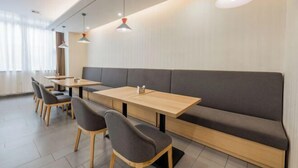 A modern dining area with wooden tables and grey upholstered benches. - Homeinn · neo (Hangzhou Xiaoshan Train South Station Tonghuizhong Road Subway Station) (Hangzhou)