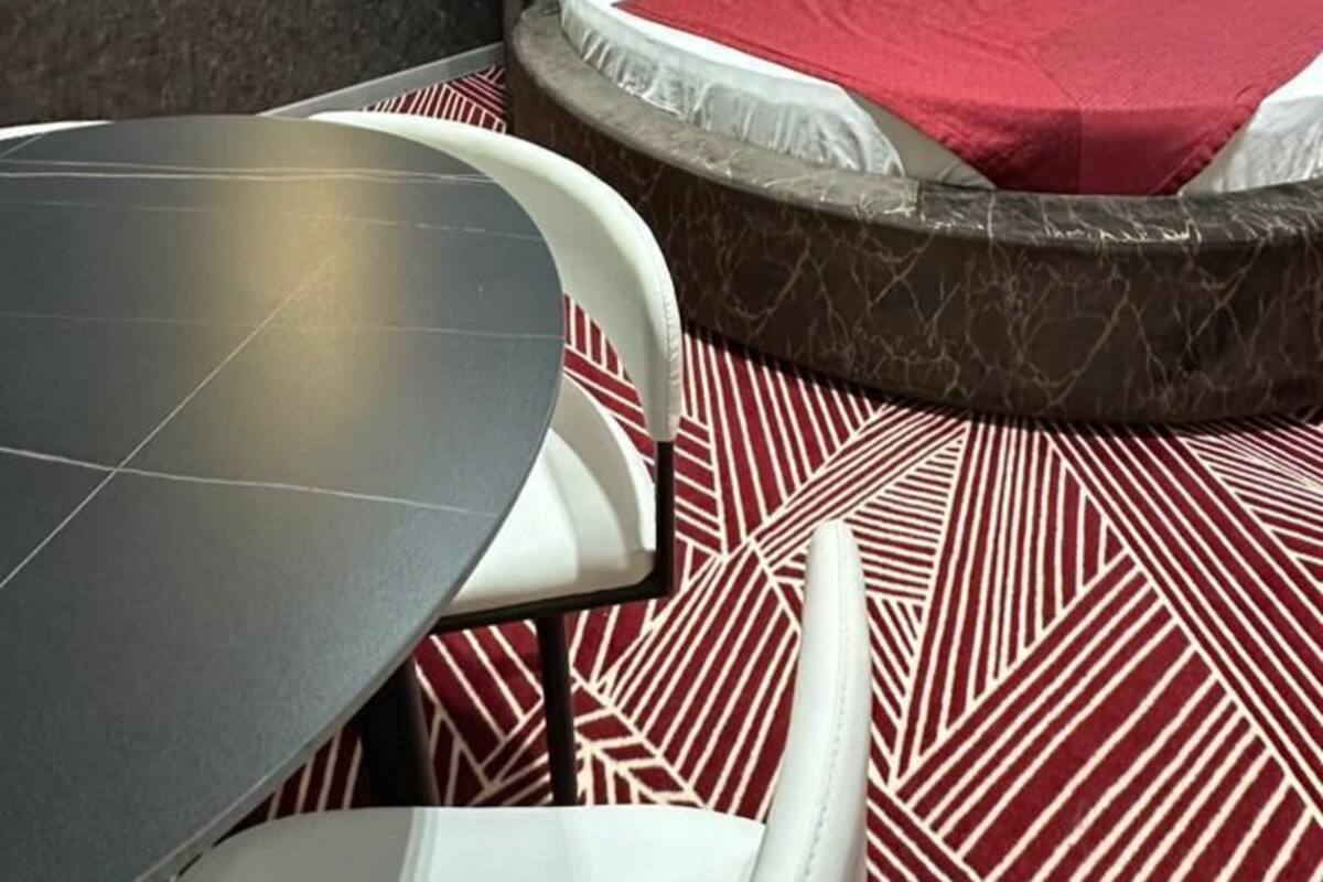 A modern hotel room with a bed, a table, and chairs.