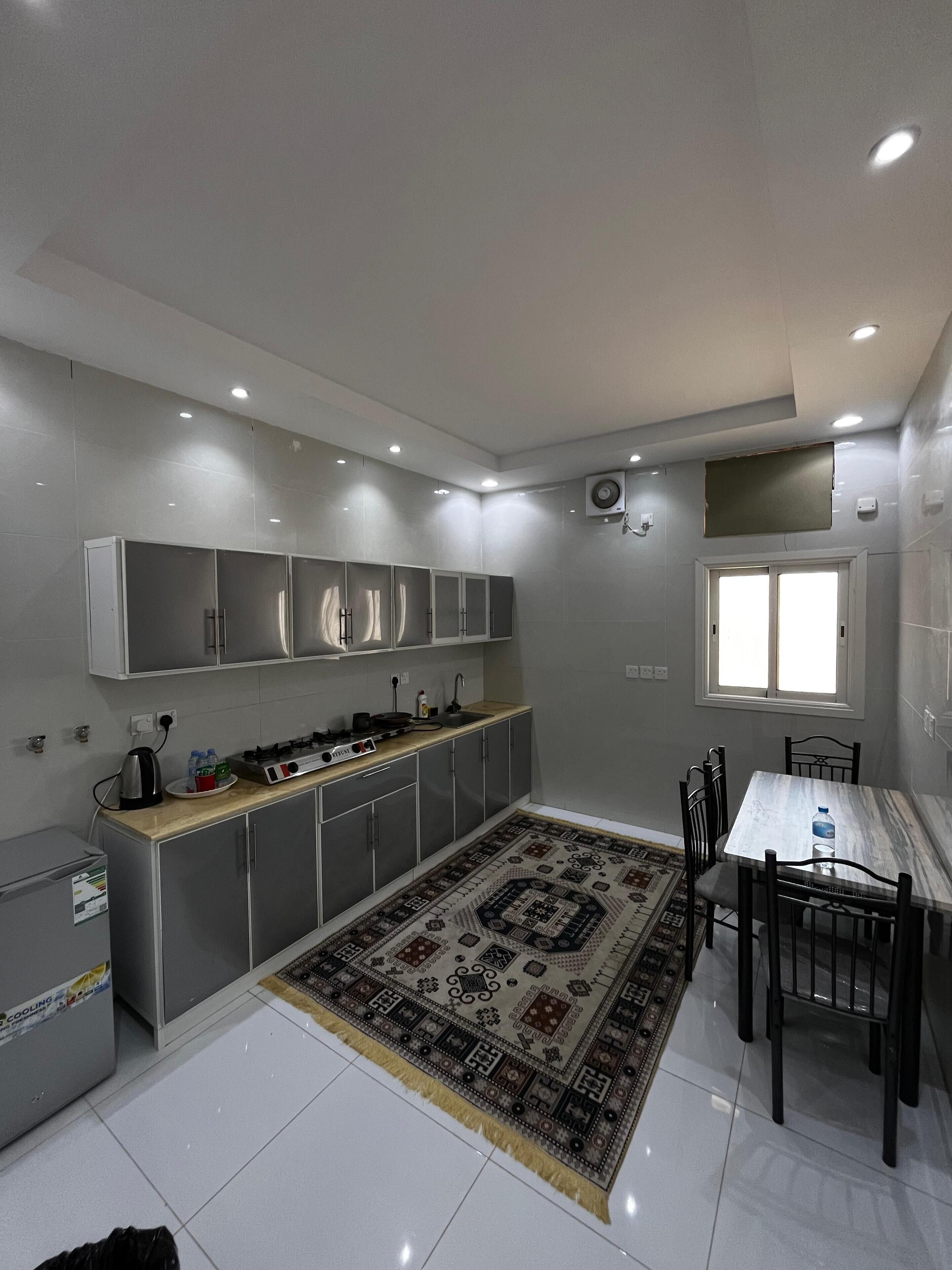 A modern kitchen with grey cabinets, a central island, and a dining area with a table and chairs.