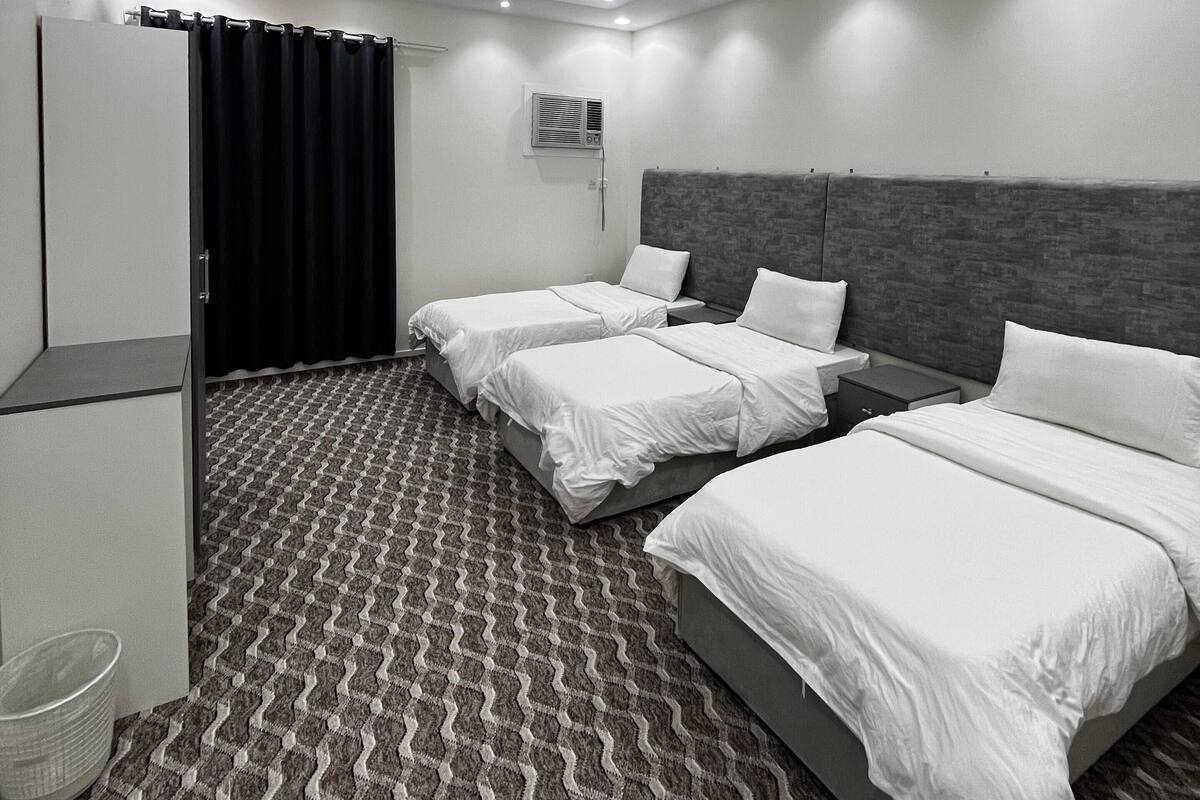 Ein modernes Hotelzimmer mit zwei Einzelbetten, einem Kleiderschrank, einer Klimaanlage und einem gemusterten Teppich.