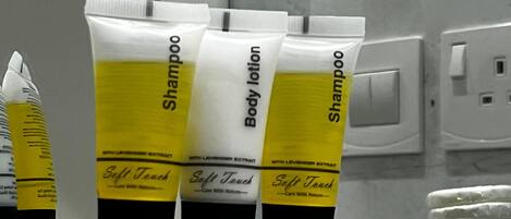 Three toiletries on a glass shelf in a bathroom.