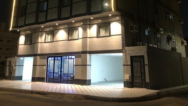 En bygning med flere etager, en markant facade med lys, store vinduer og en lukket indgang.