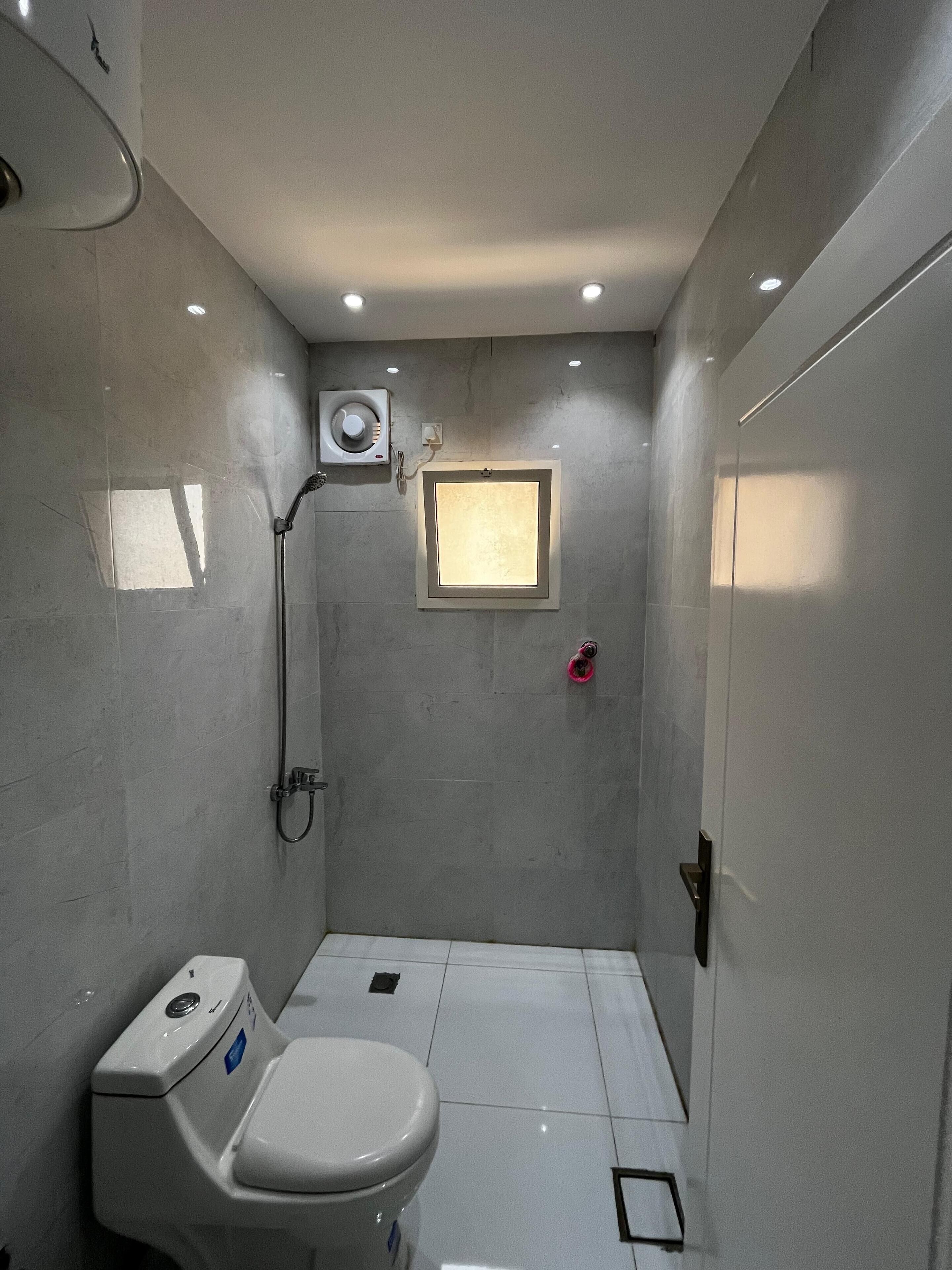 A small, modern bathroom with a toilet, a shower, and a window.