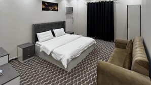 Et moderne hotelværelse med en stor seng, en sofa, et skrivebord og et mønstret tæppe.