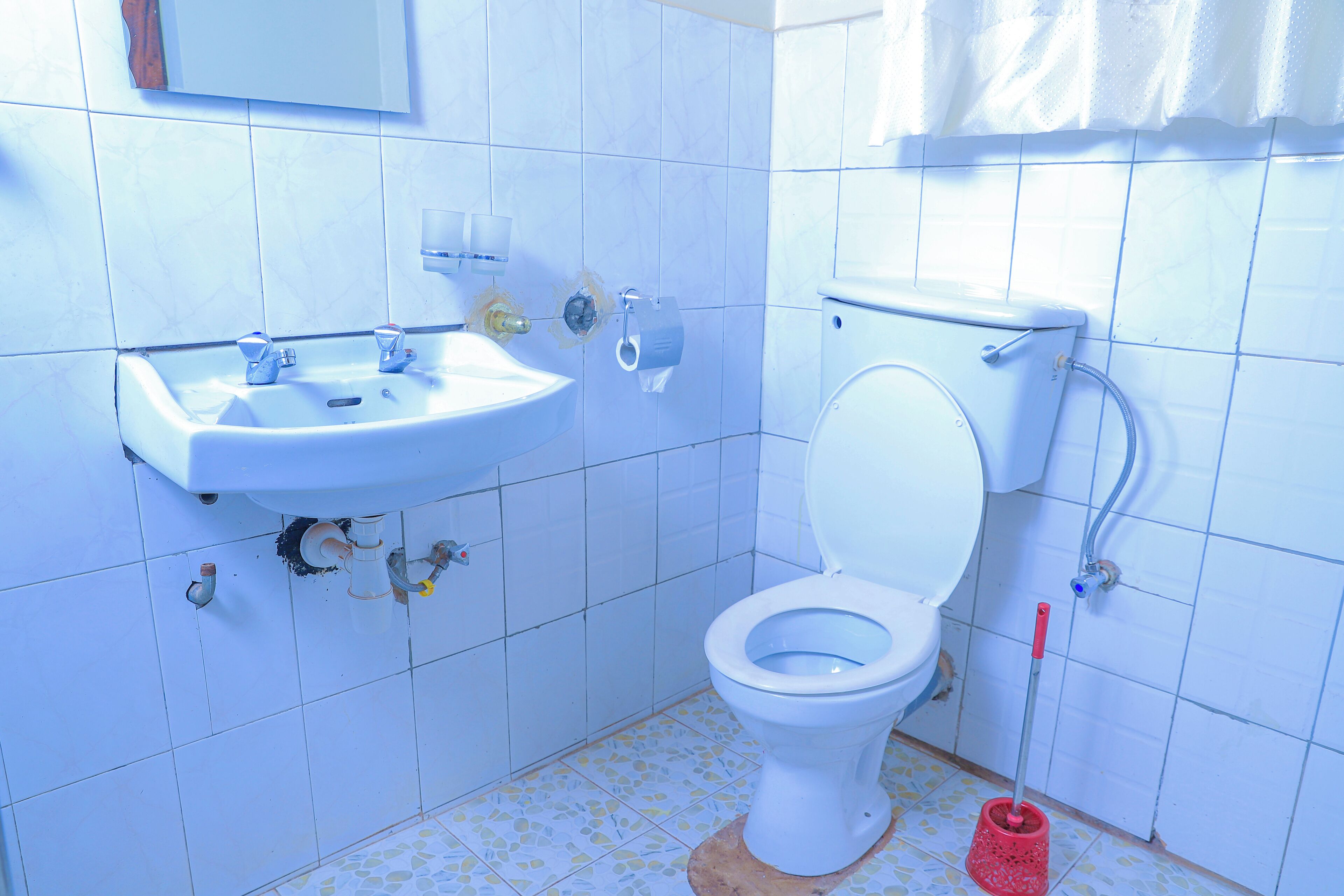A bathroom with a sink, toilet, and mop.