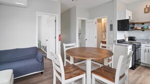 Une cuisine moderne avec des meubles blancs, une cuisinière noire et une table à manger en bois, assortie de chaises blanches.