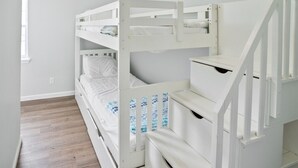 Un lit superposé avec un plancher en bois et des murs blancs.