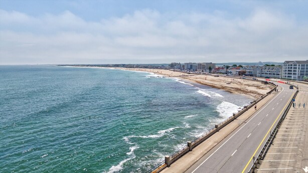 Una carretera costanera amb una platja d'un costat i edificis de l'altre.