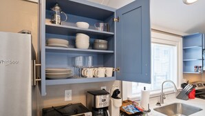 Cuina amb un armari blau integrat, un frigorífic Whirlpool i una cafetera.