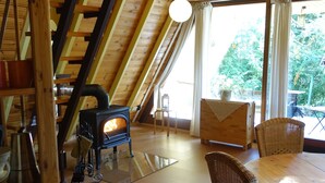 Una habitación acogedora con techo de madera, chimenea y una mesa de comedor con sillas.