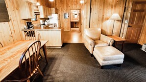 A wooden interior with a dining table, chairs, a sofa, and a kitchen area.