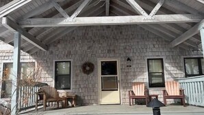 A covered porch with a brick wall, two windows, a door, and a wreath.