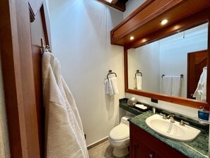 A bathroom with a wooden vanity, a sink, a mirror, and a toilet.