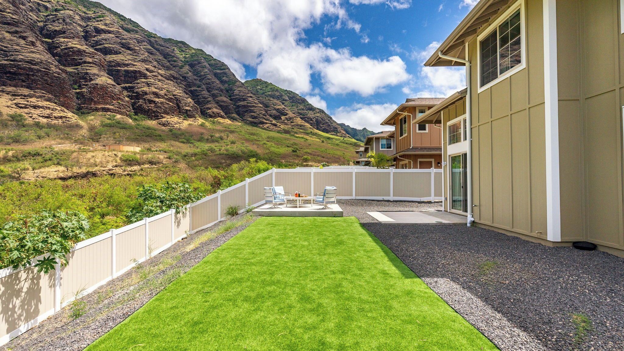 A residential property with a well-maintained lawn, a patio with outdoor furniture, and a view of a mountainous landscape.