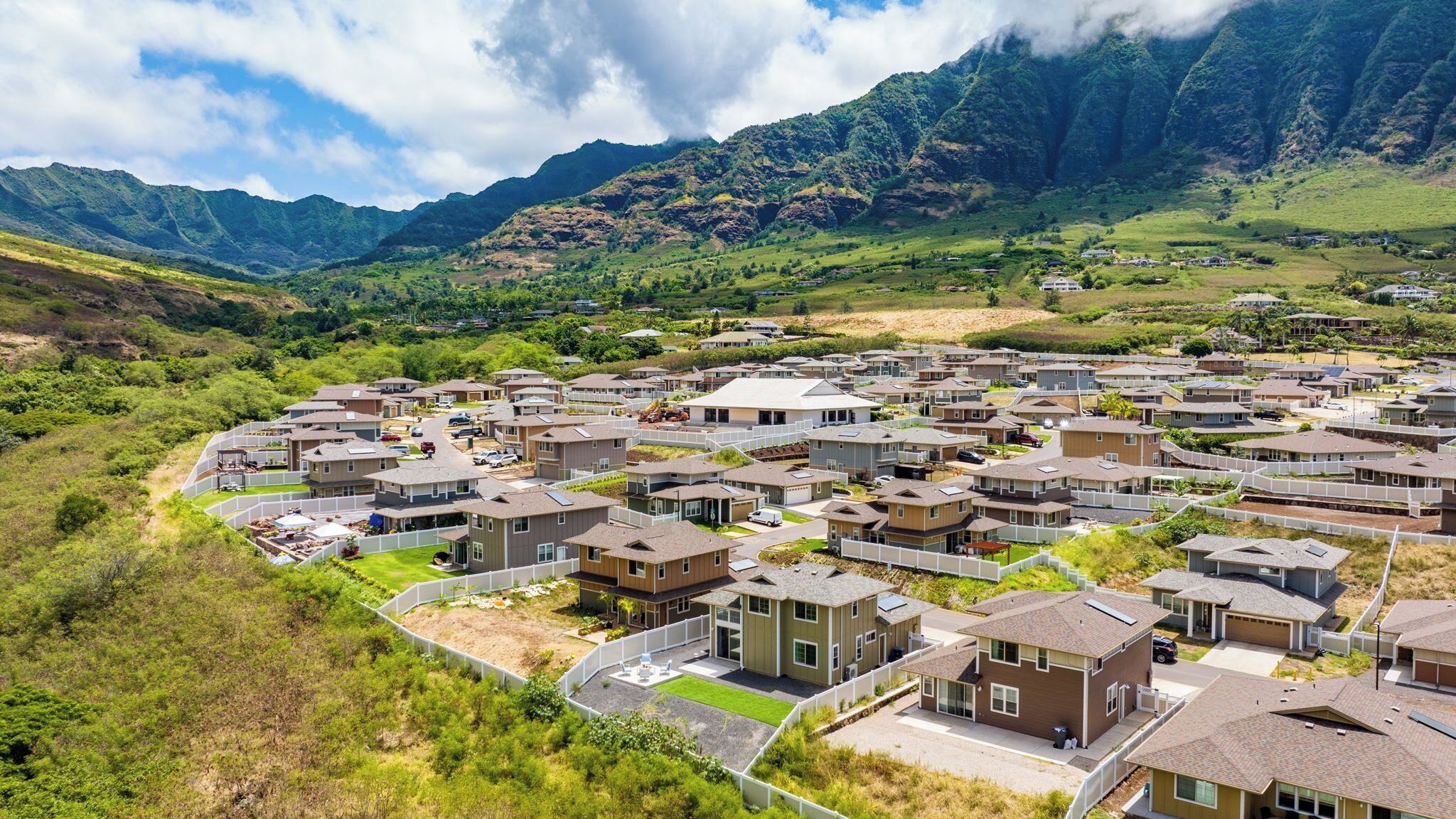 Un quartier résidentiel avec des maisons modernes, un espace public central et un paysage montagneux en arrière-plan.