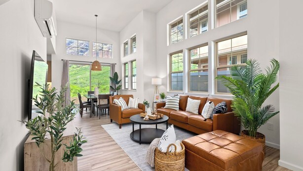 Ein großzügiges Wohnzimmer mit einem großen Fenster, einer Sofagarnitur, einem Couchtisch und einem Essbereich.