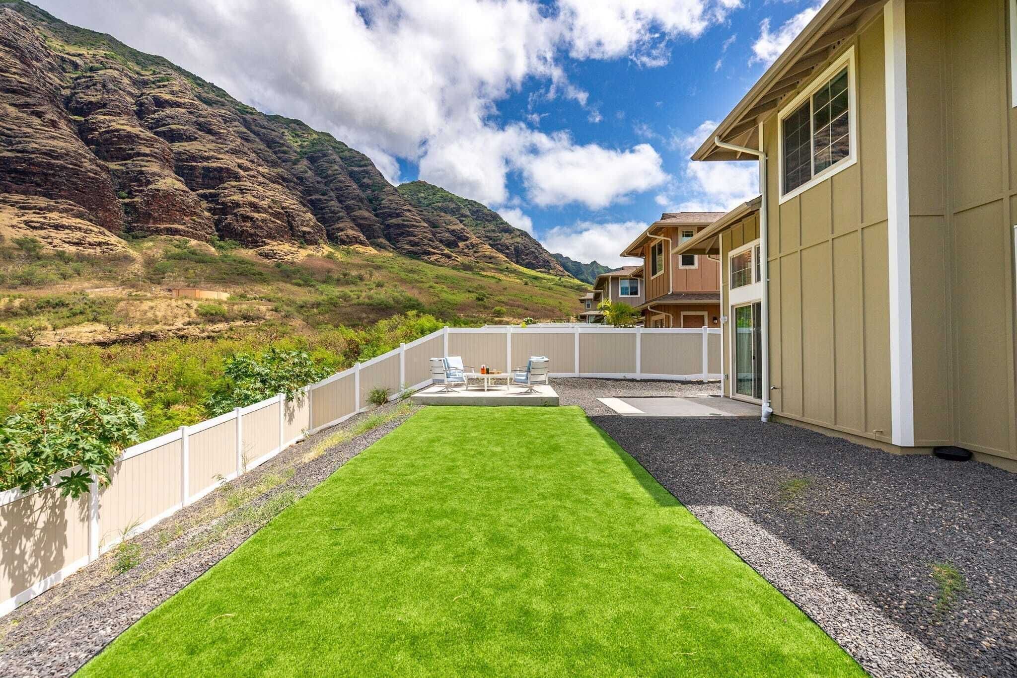 A modern house with a well-maintained lawn and a view of a mountainous landscape.