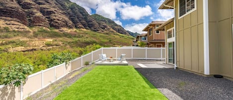 Una casa moderna con césped cuidado y vistas a un paisaje montañoso.