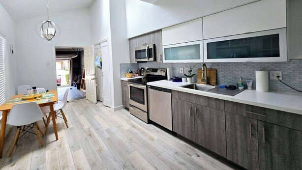 A modern kitchen with a central island, stainless steel appliances, and a large window providing natural light.