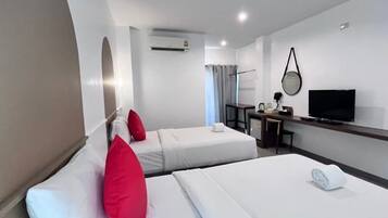 Habitación de hotel con dos camas, un escritorio, un televisor y un equipo de aire acondicionado.